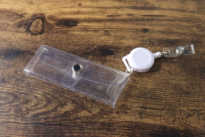 透明なリール付ポーチが木目のテーブルに置かれ、リール部分が伸びていない状態