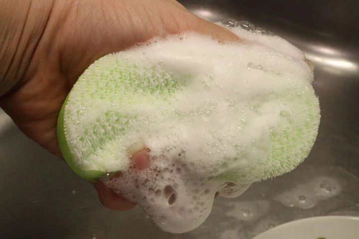 緑色のスポンジが泡だらけになり、水で濡れている様子