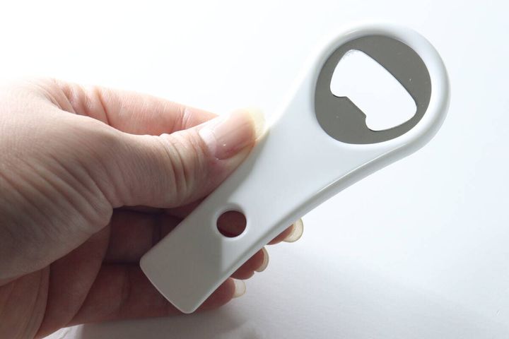女性の右手が白いオープナーの栓抜き部分を持つ