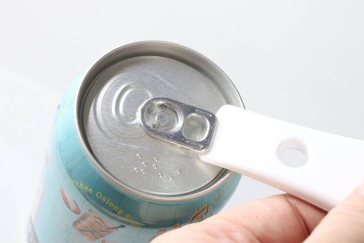 白いオープナーの先端を缶のプルタブ下に差し込む