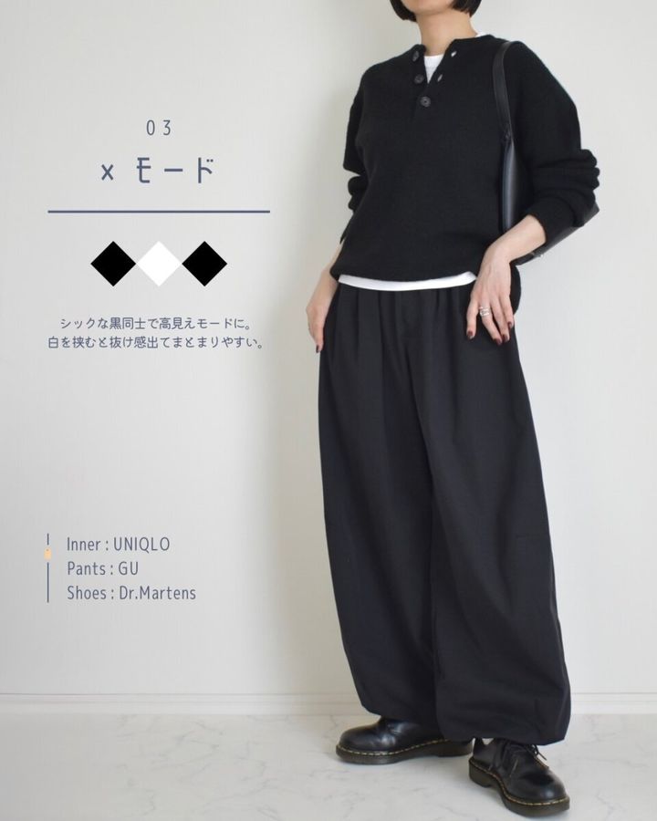 黒ニットと黒ワイドパンツに白インナーを合わせたモードな着こなしの女性