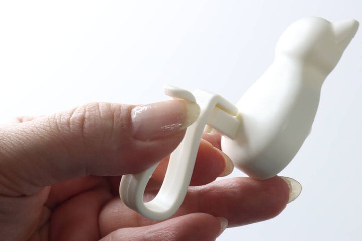 女性の手が輪ゴムフックのしっぽ部分を広げている様子