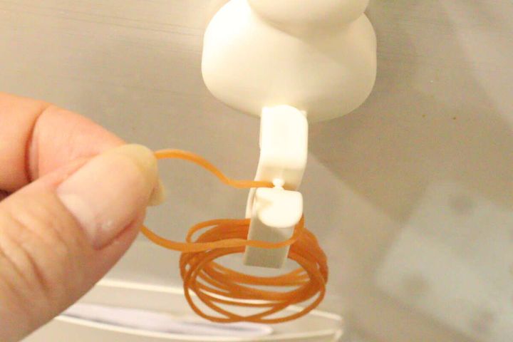 女性の指が猫デザイン輪ゴムフックから輪ゴムを1本取っている