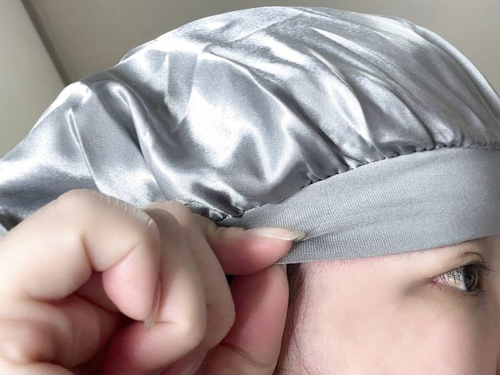 女性がシルバーのナイトキャップを着用し、額のゴム部分を確認している