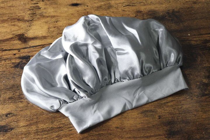 光沢のあるシルバーのナイトキャップが木目調の台に広げて置かれている