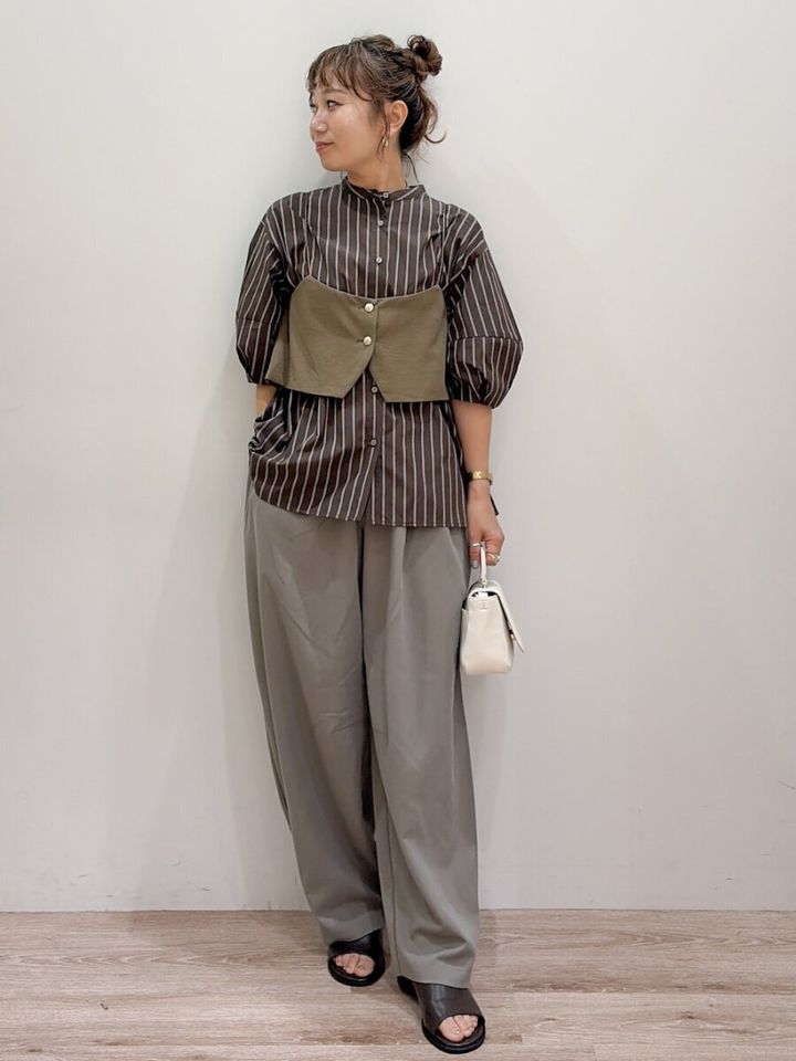 ストライプブラウスにビスチェとワイドパンツの女性