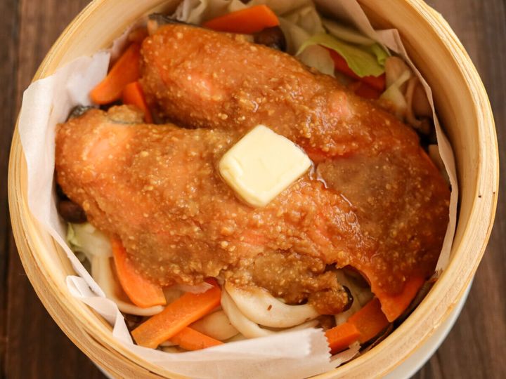 蒸し上がったせいろの中の鮭と野菜の上に、四角いバターが乗せられている