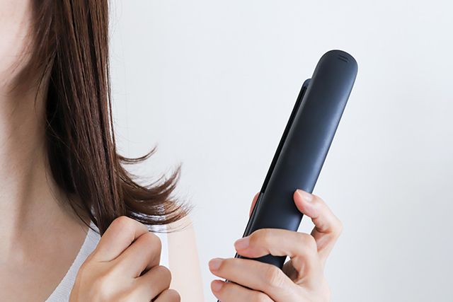 ヘアアイロンを使う女性