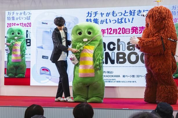 司会に3WAYポーチをつけてもらうガチャピン。ちょこんと着けているのが愛らしい！