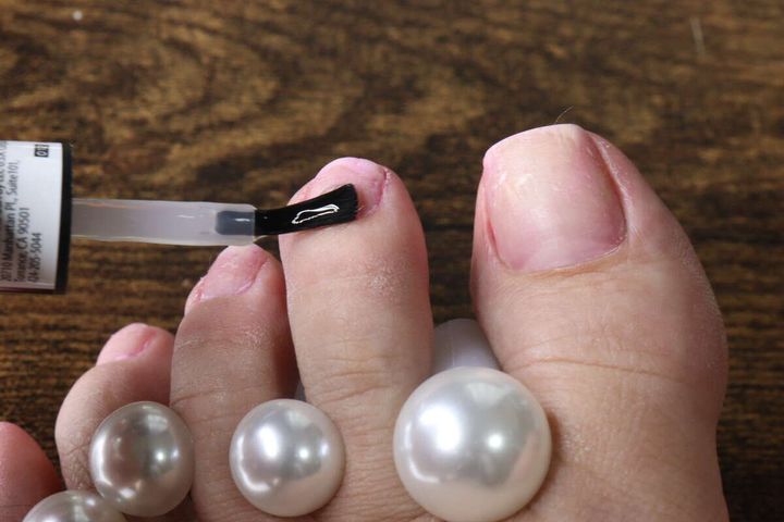 足の指の甘皮部分にキューティクルリムーバーを塗布している様子