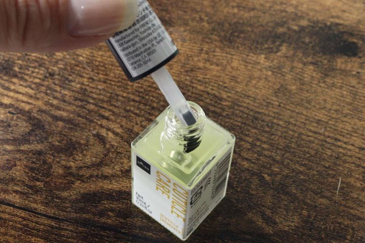 ダイソーキューティクルリムーバーのハケを容器から引き出す様子