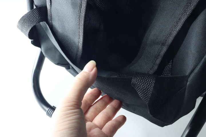 リュックの背面にあるショルダーベルト収納ポケットに指を入れて説明している