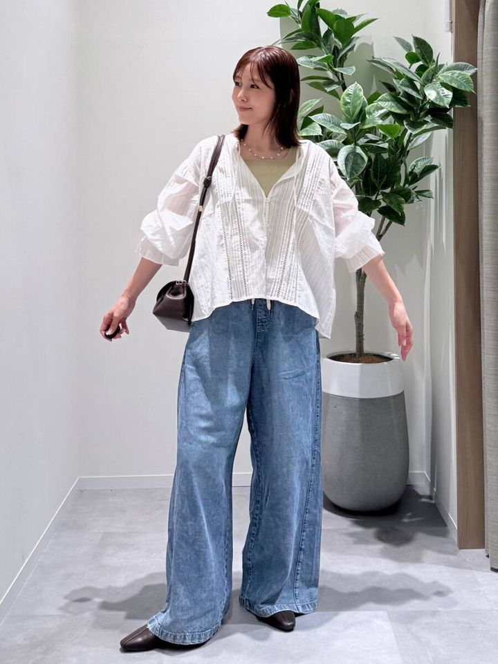 白いレースブラウスとデニムワイドパンツの女性