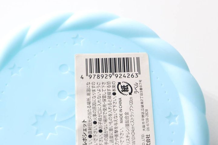 水色のサークルポシェットの裏側。JANコードと商品情報ラベルのアップ。