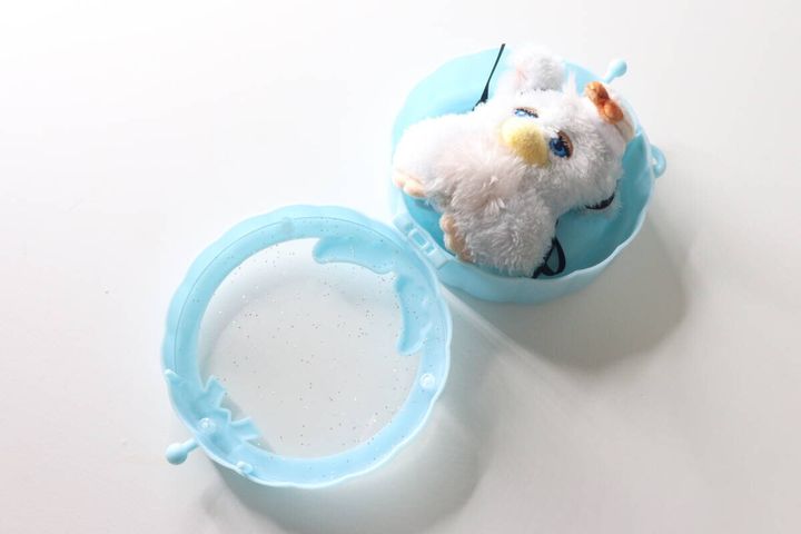 水色のサークルポシェットが開いており、白いぬいぐるみが半分入っている。