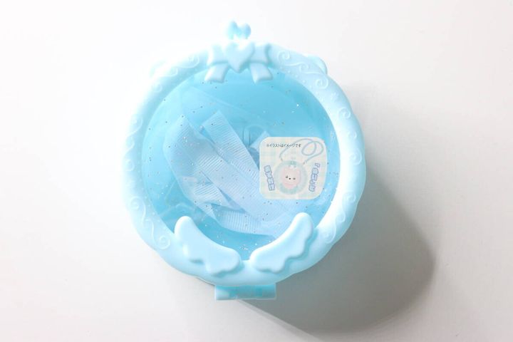 水色のサークルポシェットの全体像。中にストラップと商品ラベルが見える。