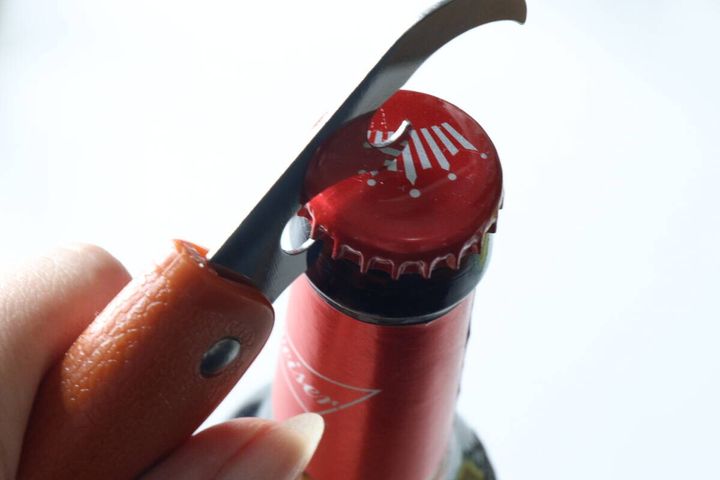 折りたたみナイフの栓抜きでビールの蓋を開ける