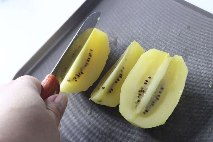 カットしたキウイとナイフでさらに切り分ける手元
