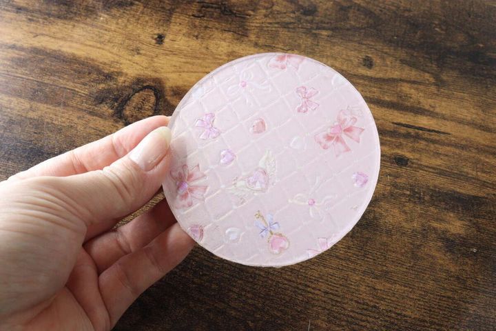 ピンクの柄のオリジナルコースターを持つ手