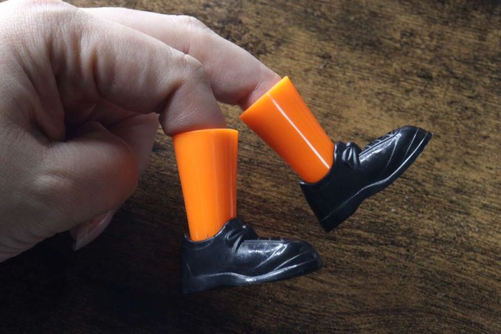 人差し指と中指にオレンジ色の指シューズをはめている手