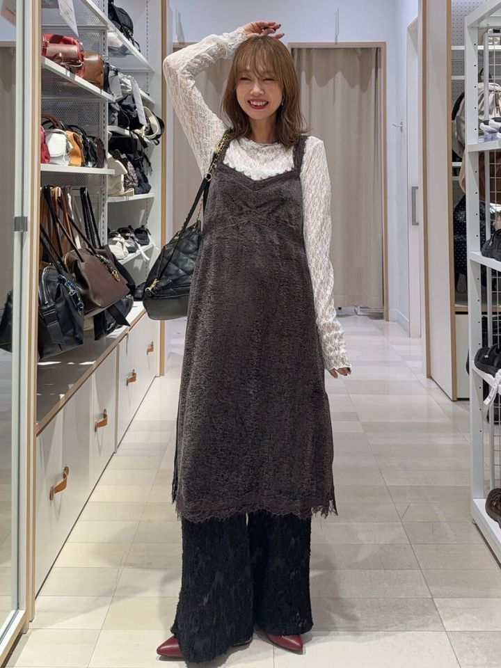 白いレーストップスとグレーのベロアキャミワンピを着て笑顔の女性