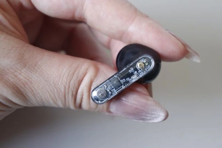 指でつまんだスケルトンデザインのワイヤレスイヤホン