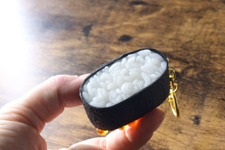 女性の手で持たれたいくらの軍艦巻きキーホルダーのシャリ部分
