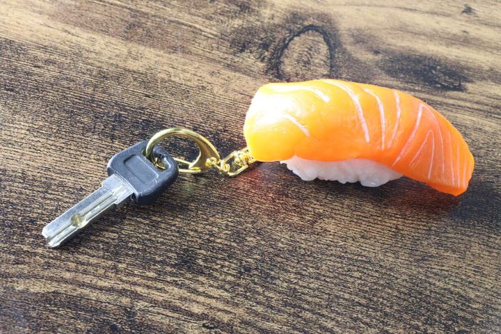 木目調のテーブルに置かれたサーモンの握り寿司キーホルダーと鍵