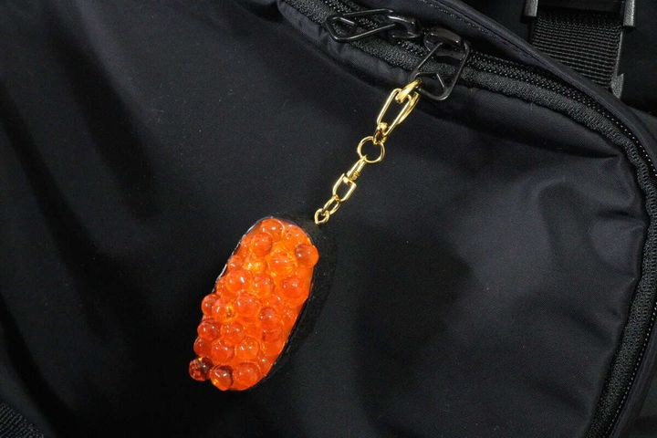 黒いバッグのファスナーに付けられたいくらの軍艦巻きキーホルダー