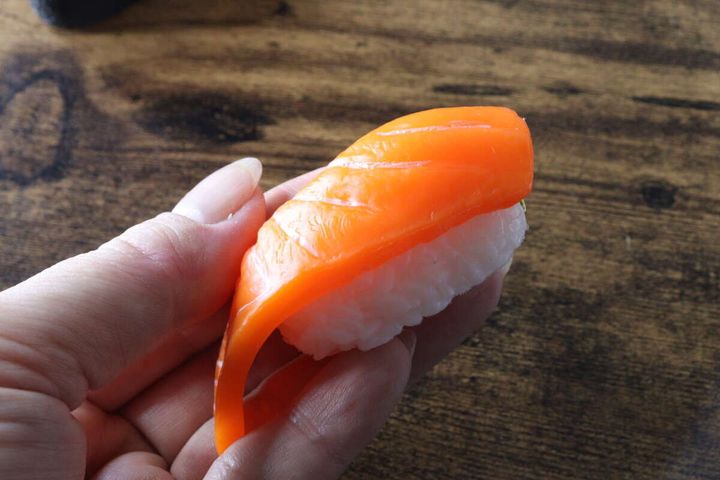 女性の手で持たれたサーモンの握り寿司キーホルダー