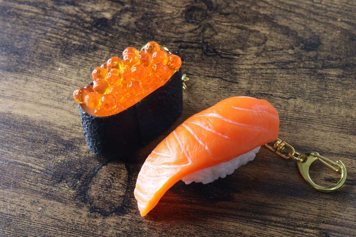 木目調のテーブルに置かれたいくらとサーモンの寿司キーホルダー