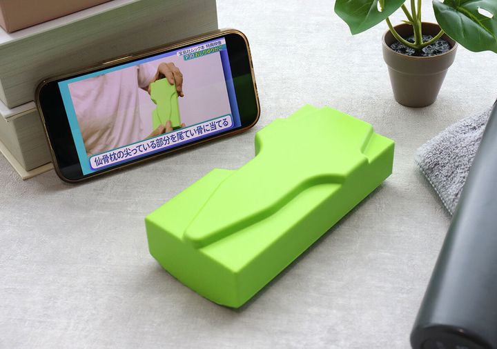 スマホで仙骨枕の解説動画を見ながら使用する様子