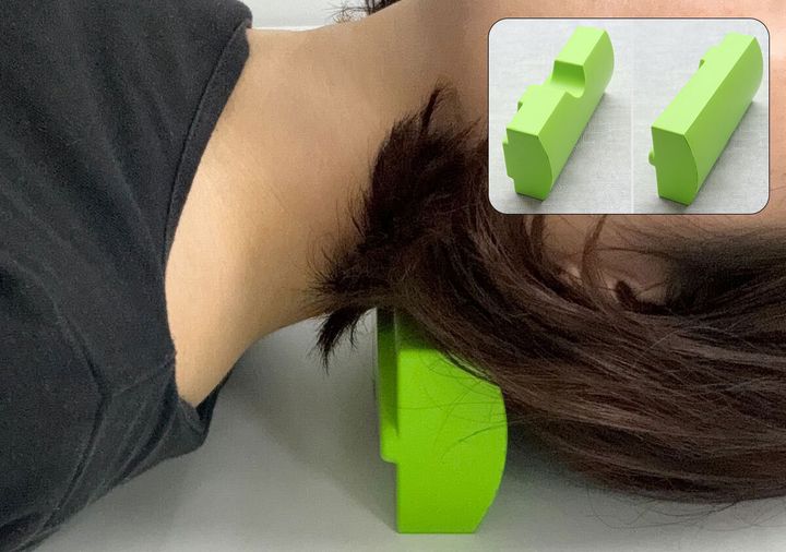 長い髪の女性が仙骨枕を首に当てて仰向けに寝ている