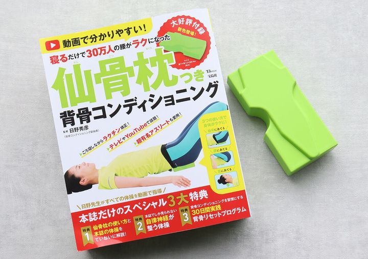 「仙骨枕つき背骨コンディショニング」ムック本と緑色の仙骨枕