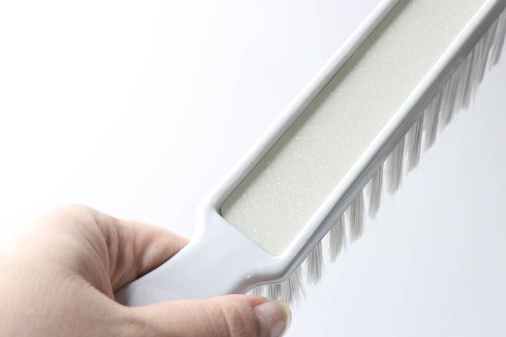 女性の手が、ほうきのブラシ上部のラメ入り部分を指で示している様子