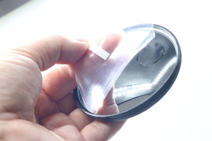 指で自転車用バックミラーの表面の保護フィルムを剥がしている様子