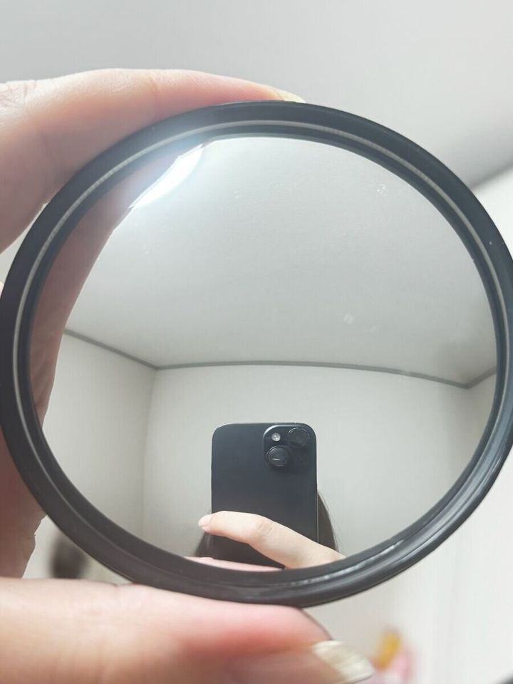 自転車用バックミラーに黒いスマートフォンと指が映り込んでいる