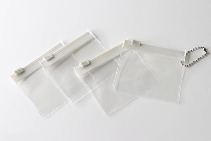 白い背景に並べられた透明なスライドポーチ4枚、1枚にはボールチェーン付き