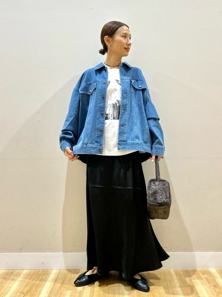 青いデニムジャケットと黒スカート、白Tシャツの女性