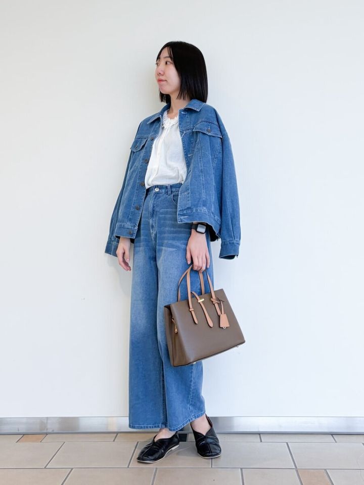 デニムジャケットとワイドパンツ、白ブラウスの女性