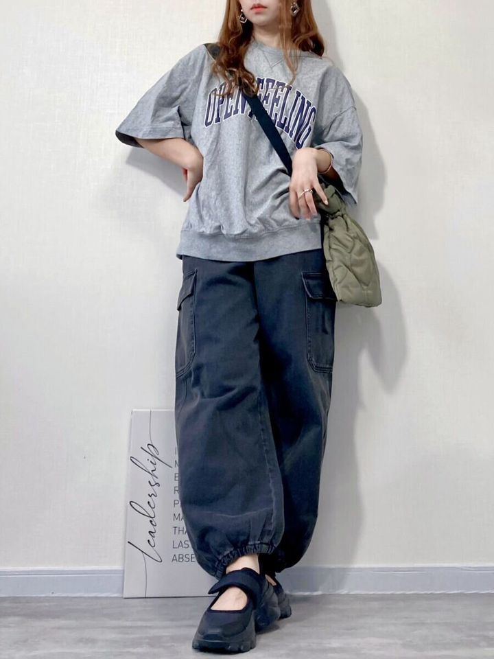グレーのロゴスウェットにグレーのデニムカーゴパンツを合わせた女性