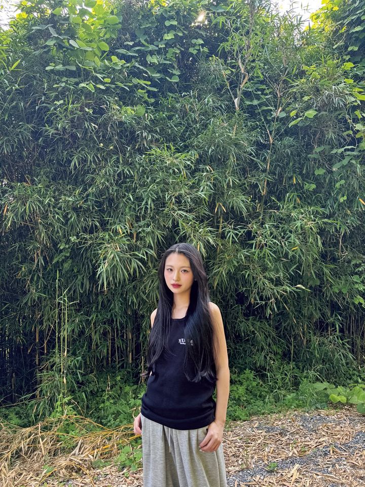 緑豊かな竹林を背景に、黒のタンクトップ姿でたたずむ桐原美月さん