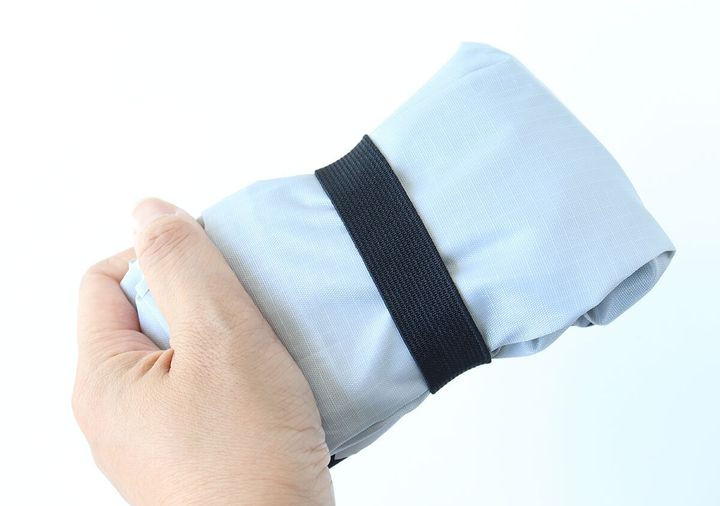 折りたたんでゴムバンドで留められたエコバッグを手に持つ。