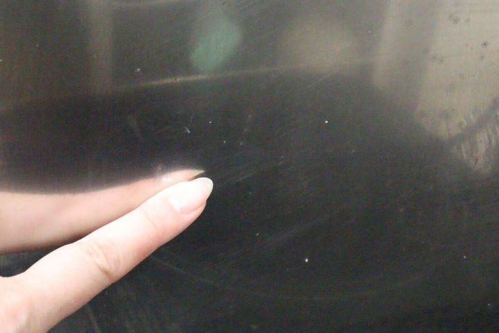 油汚れが点々と付着したコンロの表面を指で指している