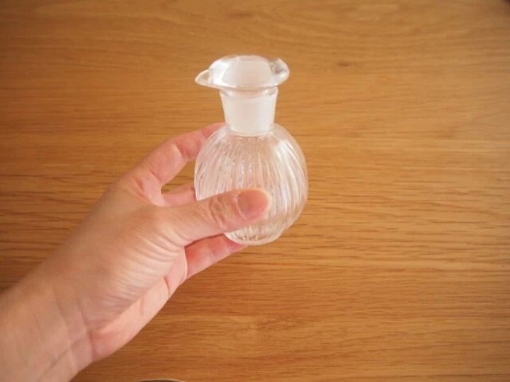 女性の手が小さなガラス製の液体調味料詰め替え容器を持っている