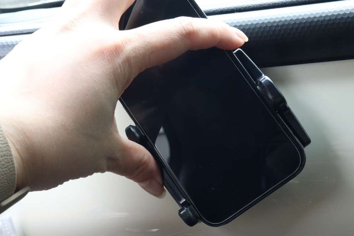 女性の手がスマホホルダーにセットしたスマホの向きを回転させている