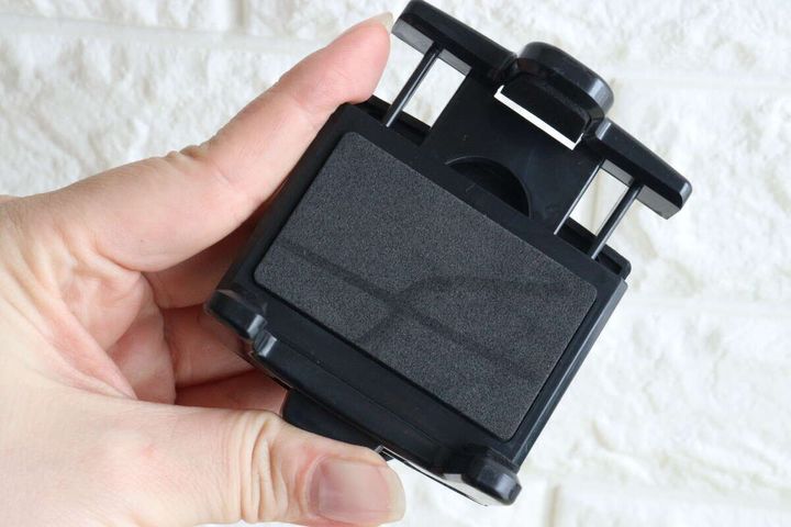 女性の手がスマホホルダーの挟む部分を広げている