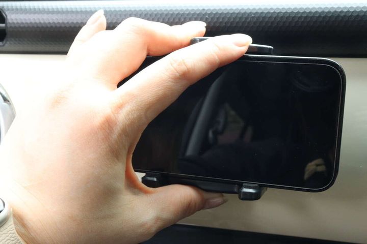 女性の手がスマホホルダーにスマートフォンをセットしている