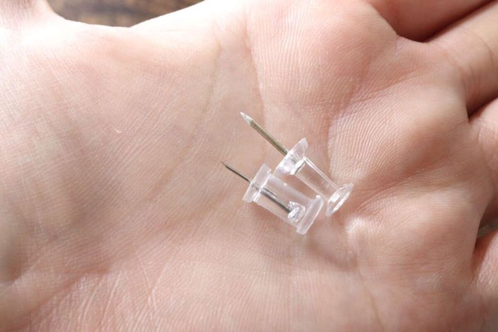 女性の手のひらにスリムプッシュピン2本が乗せられている