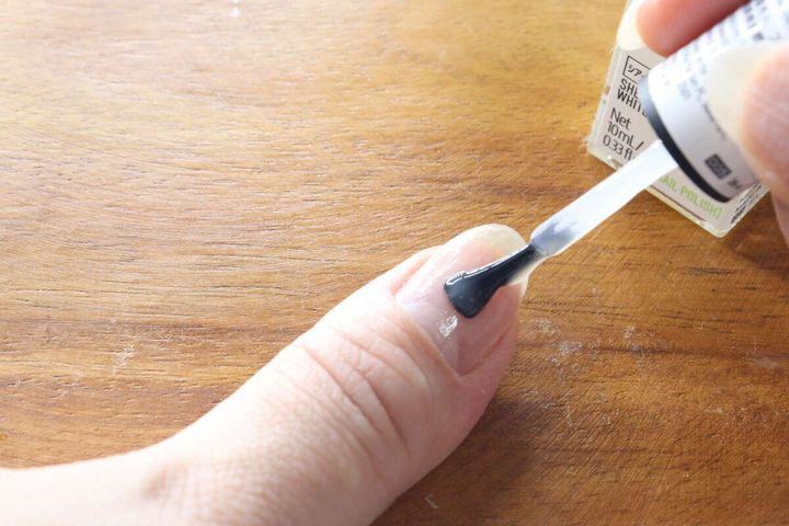 人差し指の爪にダイソーのベースコートを塗布している様子